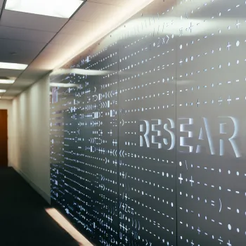Illuminated wall display in a hallway with the word “RESEARCH” surrounded by mathematical and scientific symbols.
