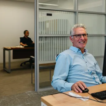 OSATT member smiling from behind computer